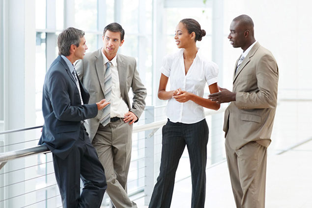 Image of coworkers standing and talking to eachother.