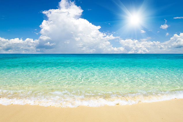 Image of bright blue calming sea with puffy white clouds.