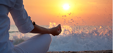 Image of a sunset with a person meditating.