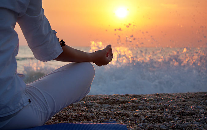 Image of a sunset with a person meditating.