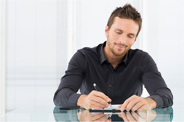 Image of man writing on paper.