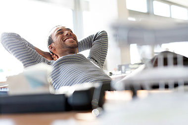 Image of man smiling and leaning back on chair at work.