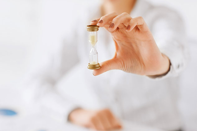 Image of women's hand holding a miniature sandglass.