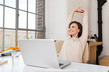 Image of women stretching arms above head while sitting at a computer desk.