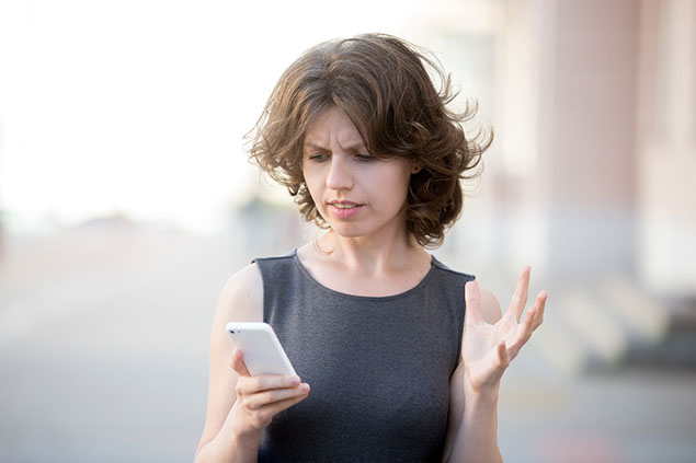 Image of women looking at phone with an angry expression.