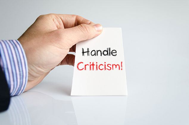 Image of hand holding note that says 'Handle Criticism.'