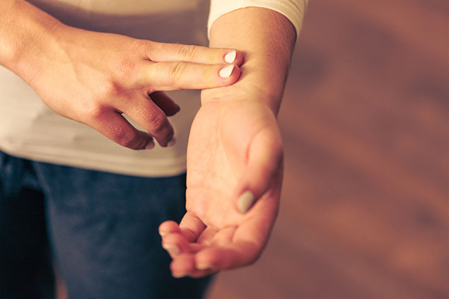 Image of person checking their pulse from the wrist.