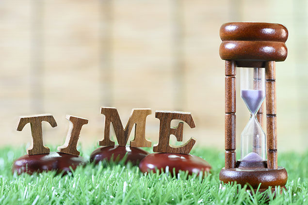 Image of sandglass with the word "time" cutout made of wood.