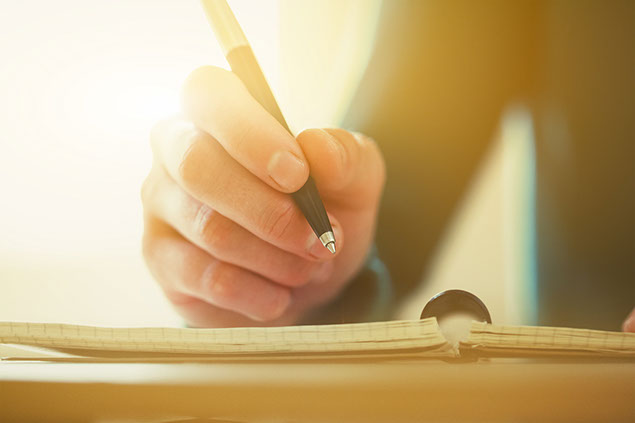 Image of female hands writing with a pen and paper.