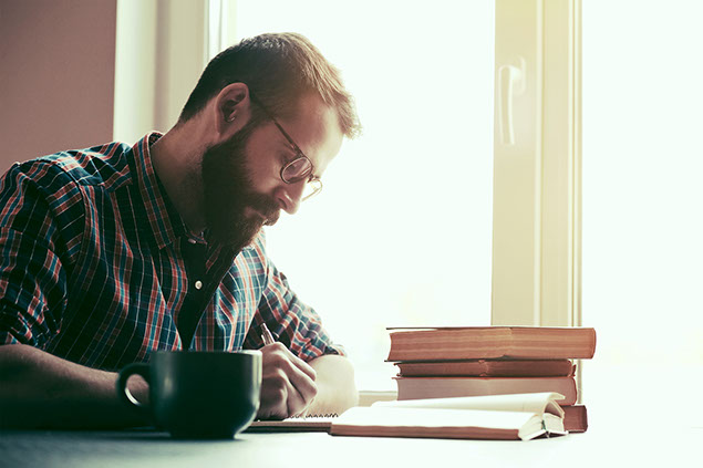 Image of man writing with pen and paper.