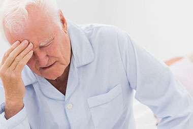 Image of older man sitting on bed.