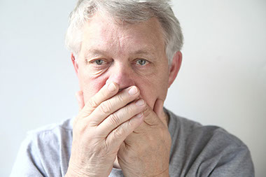 Image of man holding hands over mouth.
