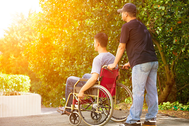 Image of a caregiver helping a man in a wheelchair.