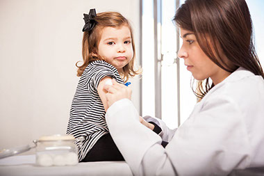 Image of toddler getting a shot by a doctor.