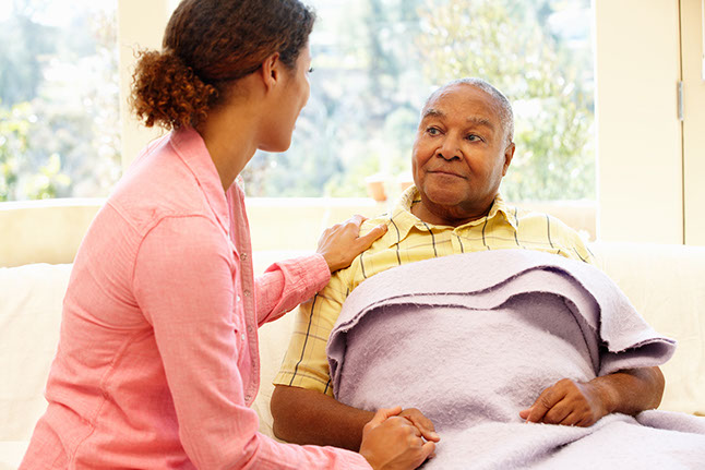 Image of mature male with a family member holding his hand in comfort.