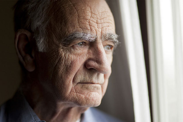 Image of older man looking outside the window.