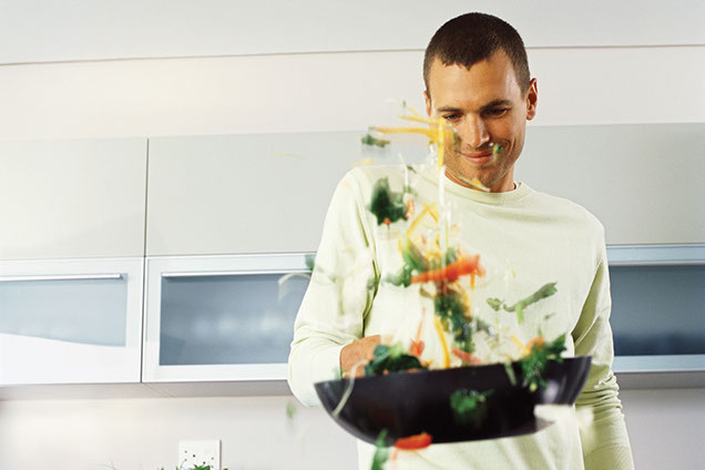 Image of a man pan stirring vegetables.