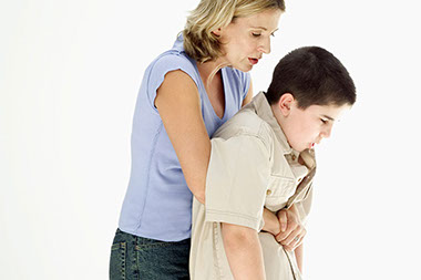 Image of an adult women giving the heimlich maneuver to a child who's choking.