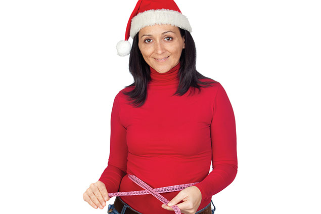 Image of women wearing a santa hat while taking her waist measurement.