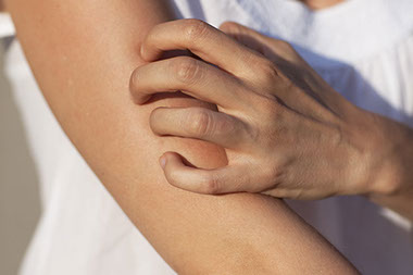 Close up image of person itching arm.