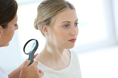 Image of doctor checking a women for skin cancer.