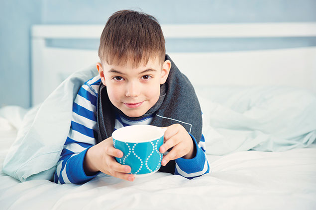 Image of child in bed holding a tea cup.