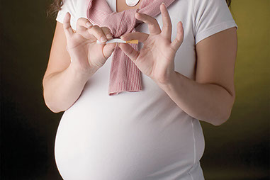 Image of pregnant women breaking a cigarette in half.