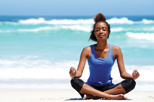 Women mediating on beach.