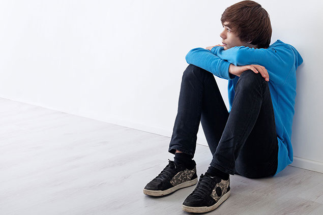 Image of young teen boy sitting on floor.