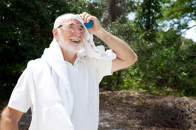 Image of older man outside wiping sweat off face with towel.