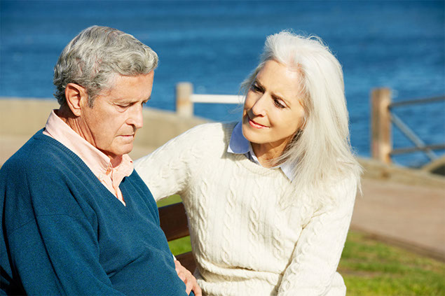 Image of couple sitting on bench along the ocean.