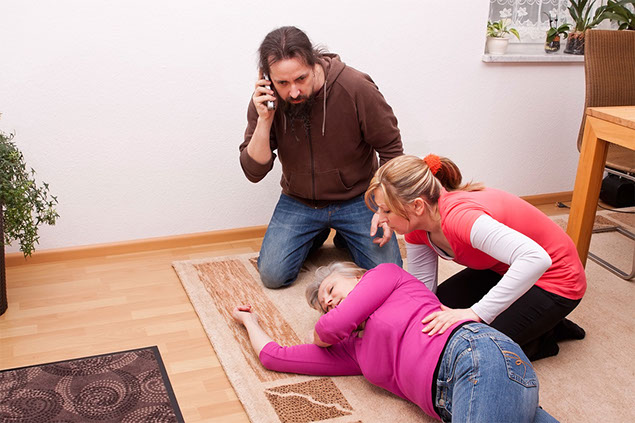 Image of women passed out on the floor, with someone helping and another person calling 911.