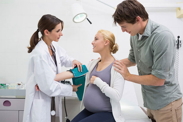 Image of pregnant women getting blood pressure checked by doctor.