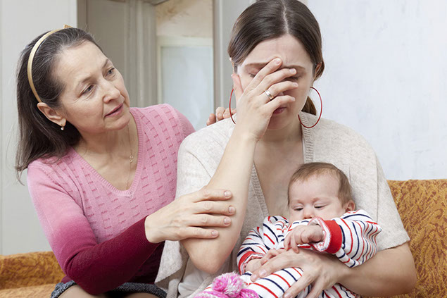 Image of sad women holding her baby while her mom consoles her.