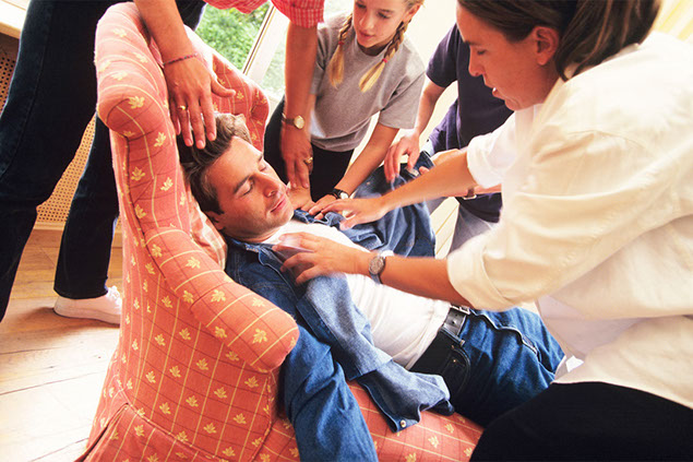 Image of fainted man while family members rush to help.