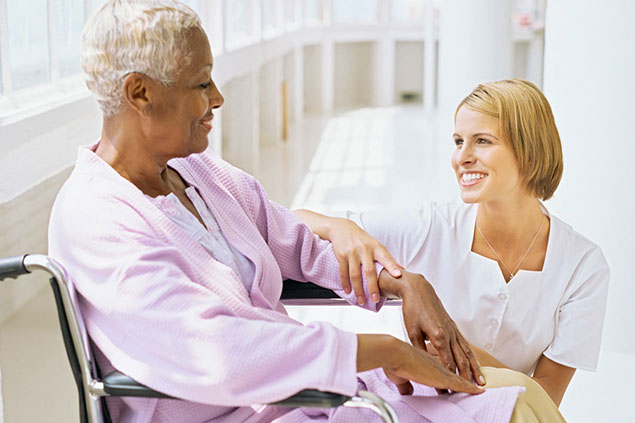 Image of nurse talking to women patient in wheelchair.
