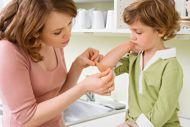 Image of a mom placing a bandage over her child's injury.