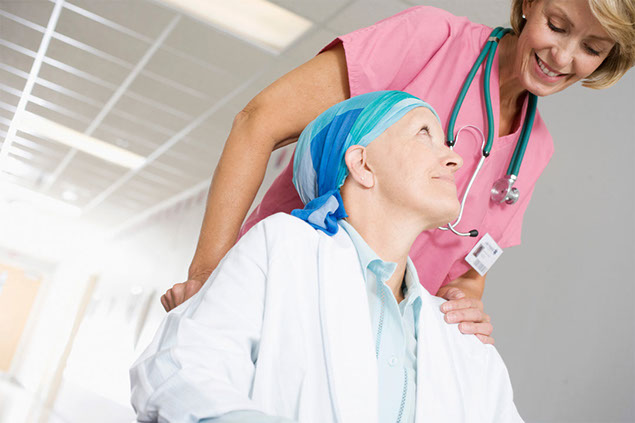 Image of cancer patient being escorted by nurse in a wheel chair.
