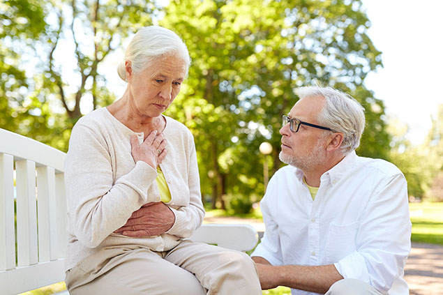 Image of women sitting on bench holding her chest.
