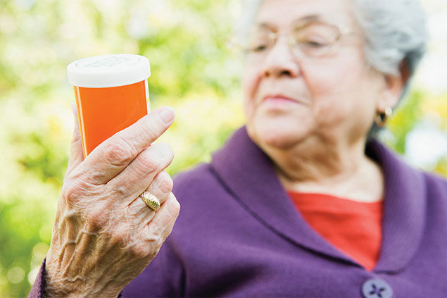 Image of older women reading pill bottle label.