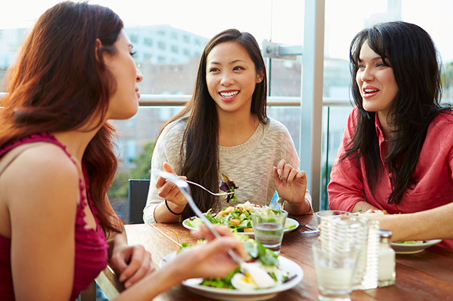 Three friends enjoying lunch at rooftop restaurant.