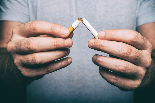Hands breaking a cigarette in half.