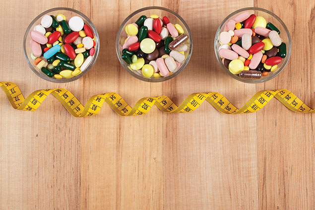 Pills in glasses with tape measure.