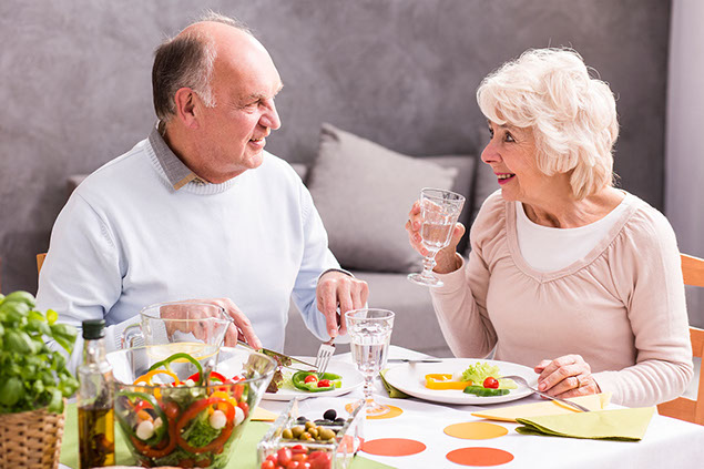 Elderly couple eating dinner.