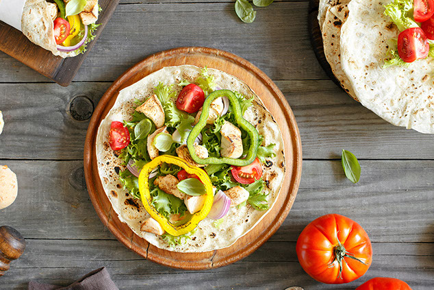 Tortilla with grilled chicken fillet, peppers, tomato, and lettuce.