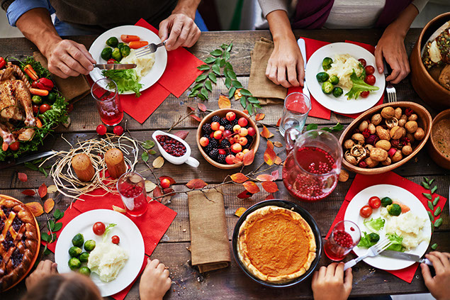 Thanksgiving dinner and family eating at table.