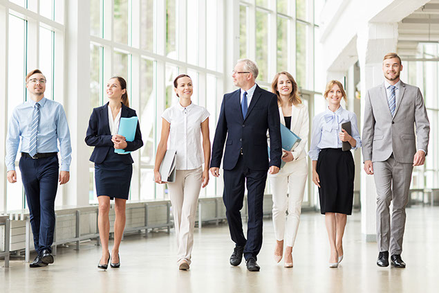 Business team with folders walking along office building and talking.