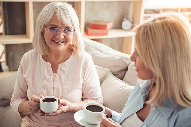 Mother and adult daughter having coffee together.