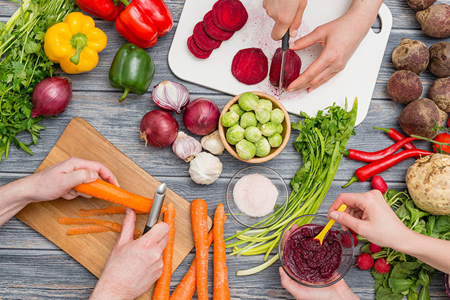 Hands cutting vetegables and preparing food.