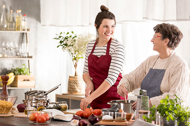 Happy, young woman cooking dinner with grandmother.